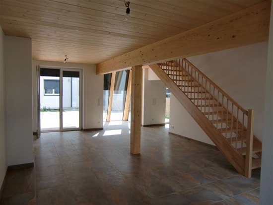 Wohnzimmer des Massivholzhauses mit Sichtholz-Decke und verputzten Wänden